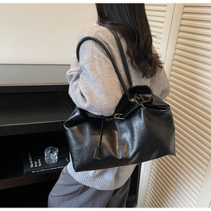 Detail of minimalist black leather tote bag with elegant tassel and smooth glossy finish