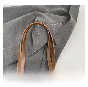 Close-up of the vintage brown leather tote bag handle with fine stitching and soft texture