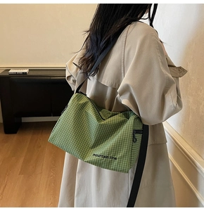 Detail of green checkered canvas crossbody bag with Mountain Line text and wide strap