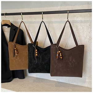 Detailed close-up of suede tote bags in brown and black with unique wooden bead tassels