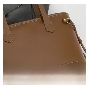Close-up of brown leather tote bag showing matte texture and reinforced stitching details