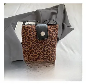Detail showing brown leopard print bucket bag with black leather flap and silver buckle