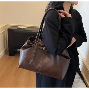 Detail of a dark brown faux leather tote bag with a smooth texture and hanging tag detail