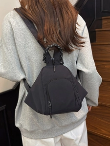 Lightweight black nylon mini backpack worn as a stylish crossbody bag on a woman's back