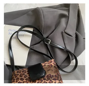 Detail of adjustable black leather strap with silver buckle on leopard bucket bag