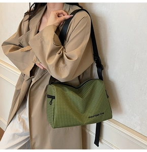 Detail of green plaid crossbody bag with mountain line text and adjustable strap