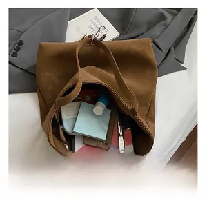 Macro view showing large interior capacity of brown suede tote bag with daily items