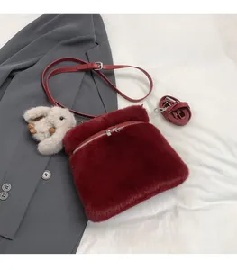 Détail du sac à bandoulière en peluche bordeaux avec fermeture éclair et breloque lapin
