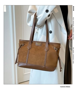 Detail of vintage brown suede tote bag with drawstring side and leather trim texture