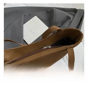 Close-up of the silver metal zipper and hardware details on the brown faux leather tote bag