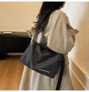 Checkered canvas crossbody bag with Mountain Line print worn over a khaki trench coat