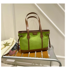 Detail of green suede tote bag with brown leather trim and drawstring side accents