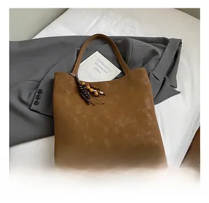 Detail of brown suede tote bag with vintage wooden bead tassel and matte texture