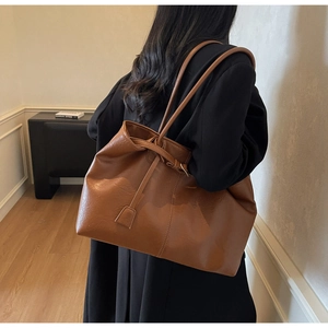 Detailed view of caramel leather tote bag showing smooth texture and long shoulder straps