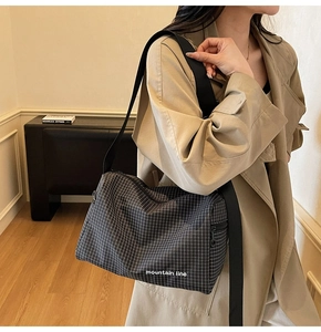 Detail of black grid canvas crossbody bag with wide strap and mountain line text print