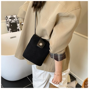 Close-up of black suede bucket bag featuring a round silver embossed metal buckle detail