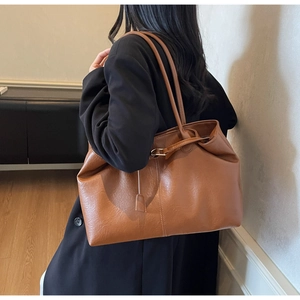 Brown faux leather tote bag with vertical stitching shown on model shoulder