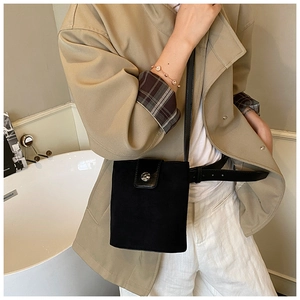 Detail of a black minimalist bucket bag with silver metal snap button on a model