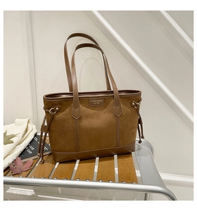 Close-up of caramel brown leather tote bag with elegant texture and metal logo plate