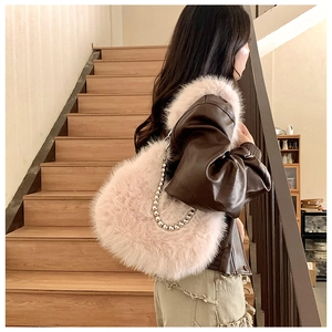 Detail of a pink heart-shaped faux fur shoulder bag with silver beaded metal chain strap