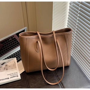Detailed view of the brown litchi grain leather texture and long handles on a tote bag