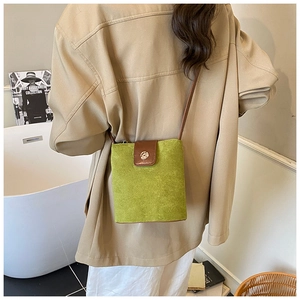 Detail of avocado green suede crossbody bag with brown leather trim and metal knob buckle