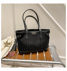 Detail of black patchwork tote bag with fashion leather label and autumn decor