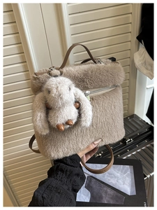 Détail d'un sac seau en peluche avec breloque lapin et anses en cuir marron