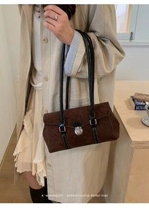 Close-up of brown suede shoulder bag featuring silver metal buckles and retro finish