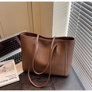 Close-up of pebble-grain brown leather tote bag texture with natural window light