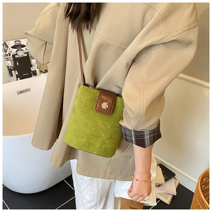 Green suede bucket bag with brown leather flap and magnetic closure shown in life style