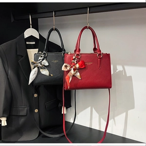 Close-up of lychee textured leather tote bags with silk scarf and gold branding