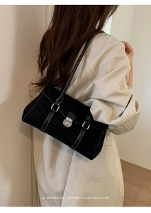 Model wearing retro black suede underarm bag with silver buckle and white stitching detail