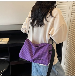 Close-up of purple checkered crossbody bag with adjustable black strap and logo