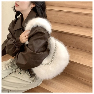 White faux fur crescent bag with decorative silver bead chain shown on a model