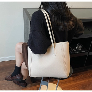 Close-up of cream large tote bag with lychee grain leather texture on model shoulder