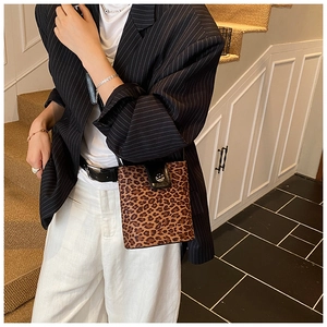 Detail of leopard print crossbody bag with black leather flap and metal buckle closure