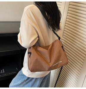Detailed back view of brown checkered canvas messenger bag with mountain line logo