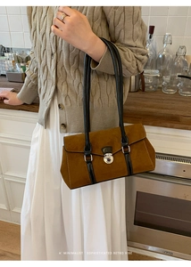 Close-up of brown suede minimalist bag with black leather straps and silver buckle detail