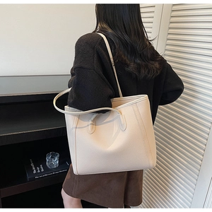 Detail of a creamy white tote bag with lychee texture shown worn as a shoulder bag