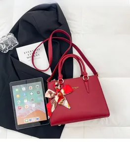 Detail of red pebbled leather handbag with silk scarf and logo on white quilted background