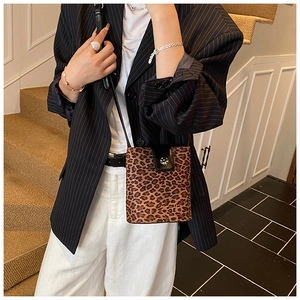Detail of leopard print crossbody bag with black leather flap and silver buckle accent