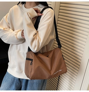 Detailed view of brown plaid canvas crossbody bag with adjustable strap and zip closure