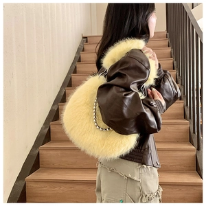 Detail of cream faux fur shoulder bag with silver bead chain strap worn by a model