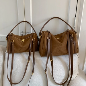 Détail de deux sacs cabas en daim marron, tailles large et petite, sur un canapé
