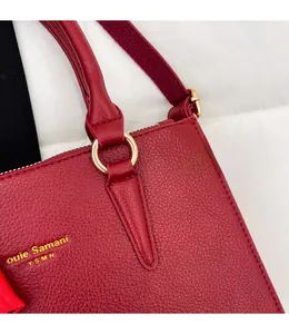 Close-up of red lychee grain leather tote bag with gold metal hardware and brand logo