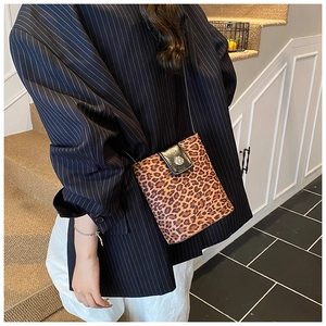 Close-up of leopard print crossbody bag with silver buckle worn with a navy blazer