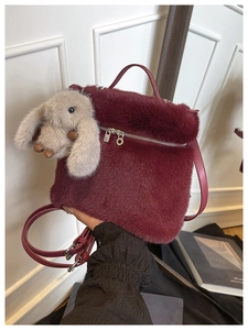 Détail d'un sac seau en fausse fourrure bordeaux avec texture douce et breloque lapin