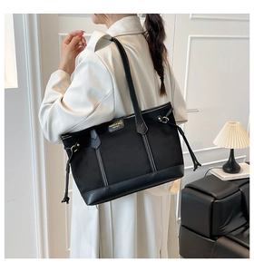 Detailed side view of a large black vintage tote bag with fringe tassels and shoulder strap