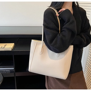 Close-up of beige lychee textured leather tote bag with long double handles and vertical stitching